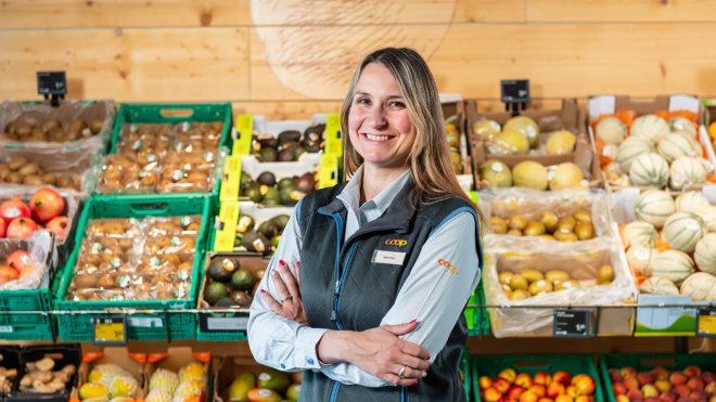 Valentina de Palma steht vor einem Coop Verkaufsregal und lächelt