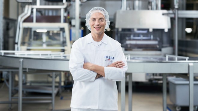Ein Mitarbeiter in der Produktionsabteilung des Schokoladenherstellers Halba lächelt in die Kamera.