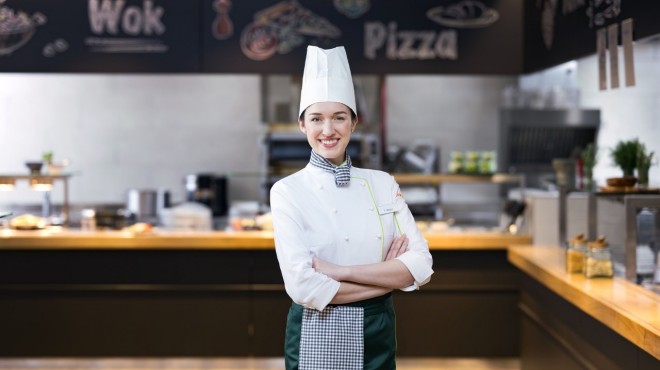 Une cuisinière souriante du restaurant Coop regarde en direction de la caméra.