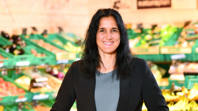 Irene Stadelmann è davanti a uno scaffale di vendita Coop e sorride.