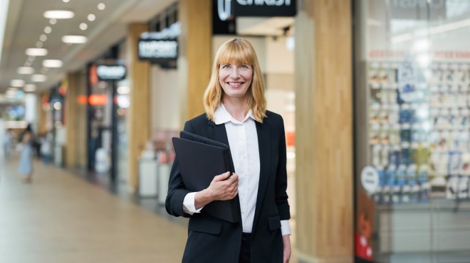 Una collaboratrice del settore Immobili di fronte ai negozi di vendita al dettaglio di un Ipermercato Coop.